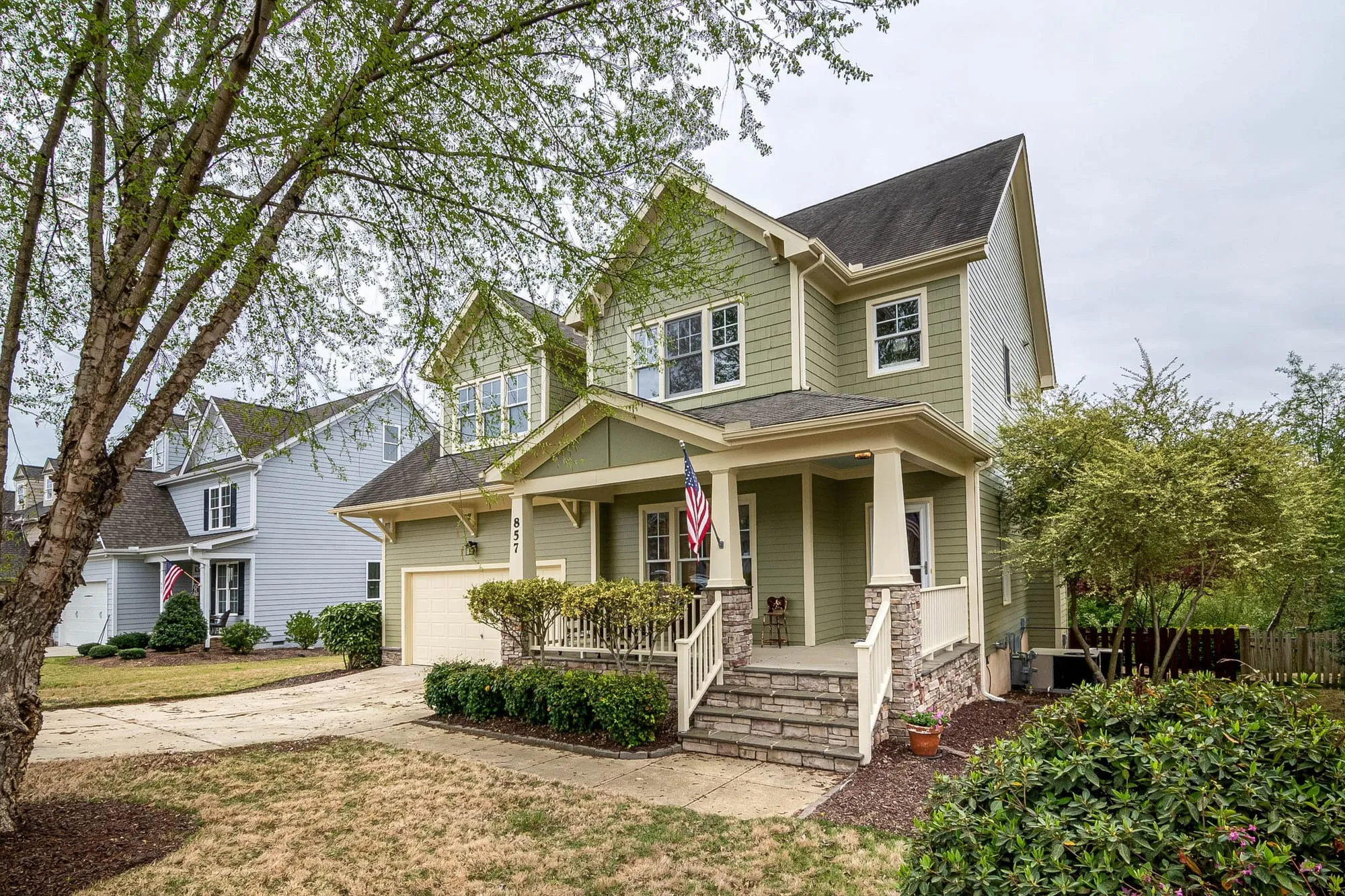 A two-story home with a covered front porch on a tree-lined residential street